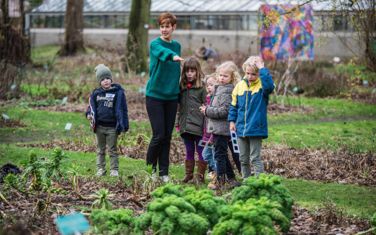 Een gids geeft uitleg aan een groepje kinderen in de plantentuin